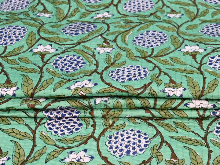 Mint green floral quilted fabric showing green and white striped reverse