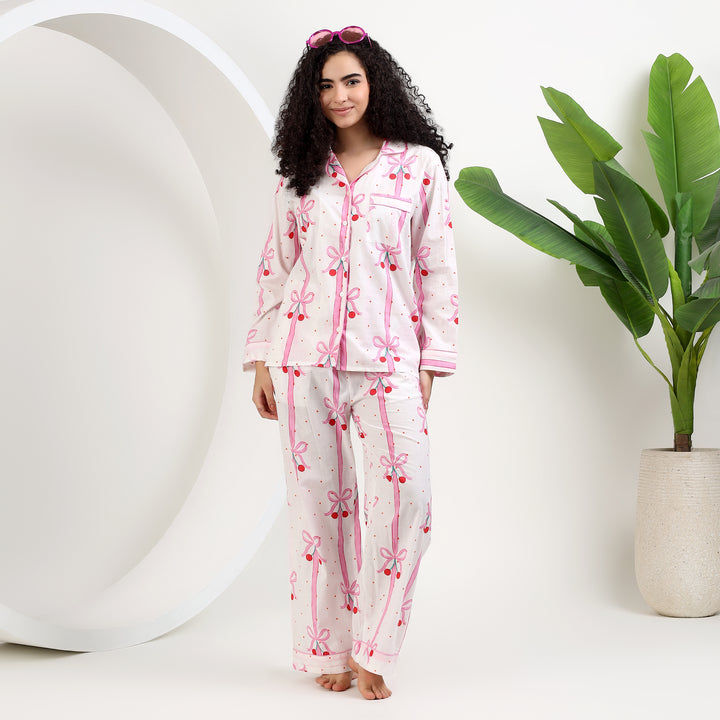 Woman in Women's Organic Cotton Holiday Pajama Set featuring white and pink bow print, ideal for cozy holiday nights.