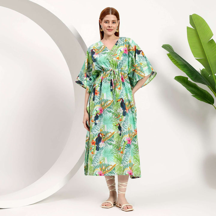 wholesale cotton kaftans for boutiques featuring a model in a colorful tropical print kaftan with a waist tie.