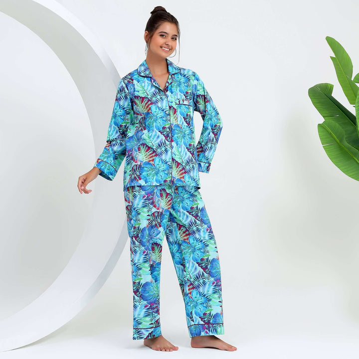 Woman wearing tropical floral cotton pajamas with vibrant leaf print against a minimalist background.