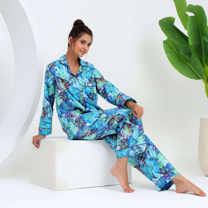 Woman wearing tropical floral cotton pajamas, featuring a vibrant floral leaf print, showcasing comfort and style.
