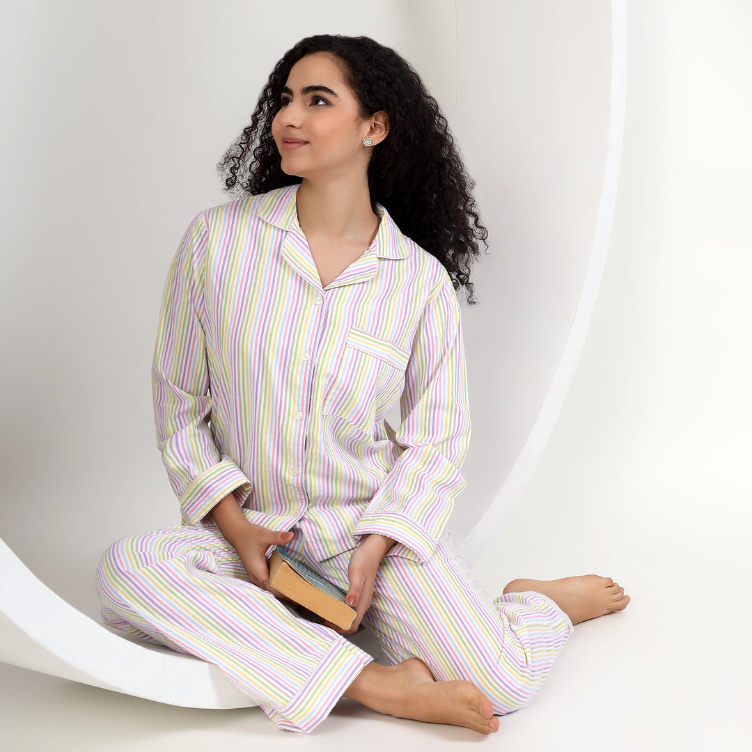 A woman in womens soft cotton pajamas for famaly matching, sitting comfortably with a book, featuring thin stripes.