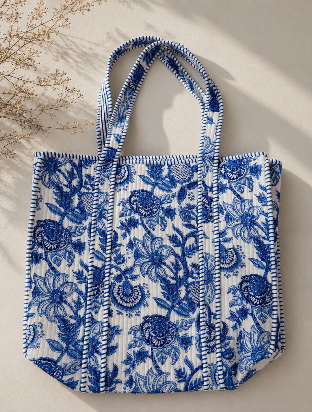 Eco-friendly handmade quilted cotton bag placed next to a reusable water bottle.