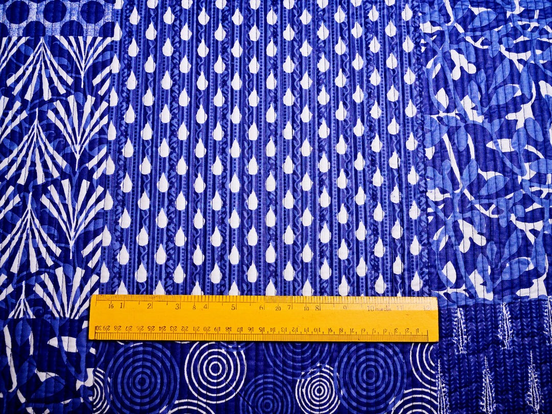 Scale placed on indigo quilt fabric to showcase the pattern dimensions and design details for crafting and décor.