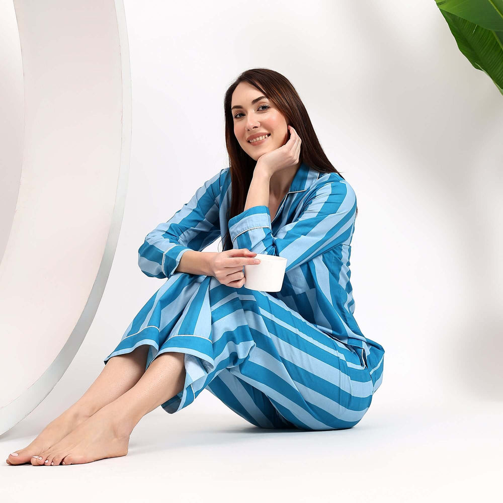 Woman in hand block striped pajamas for women sitting with a cup in blue and white striped fabric.