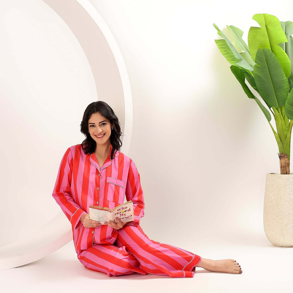 Woman sitting in cotton stripe print pajamas for women, reading a book in a stylish setting.