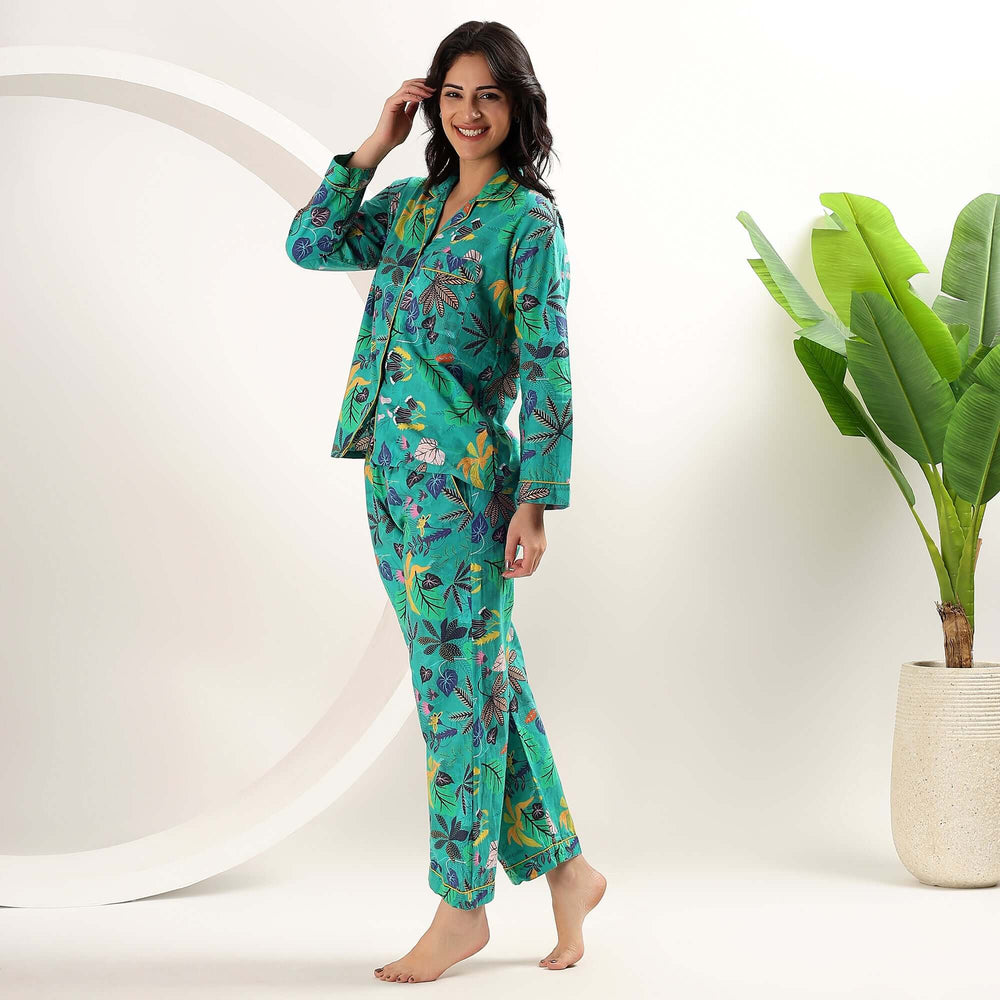 Woman wearing matching cotton pajama sets featuring a tropical floral design, perfect for lounging.