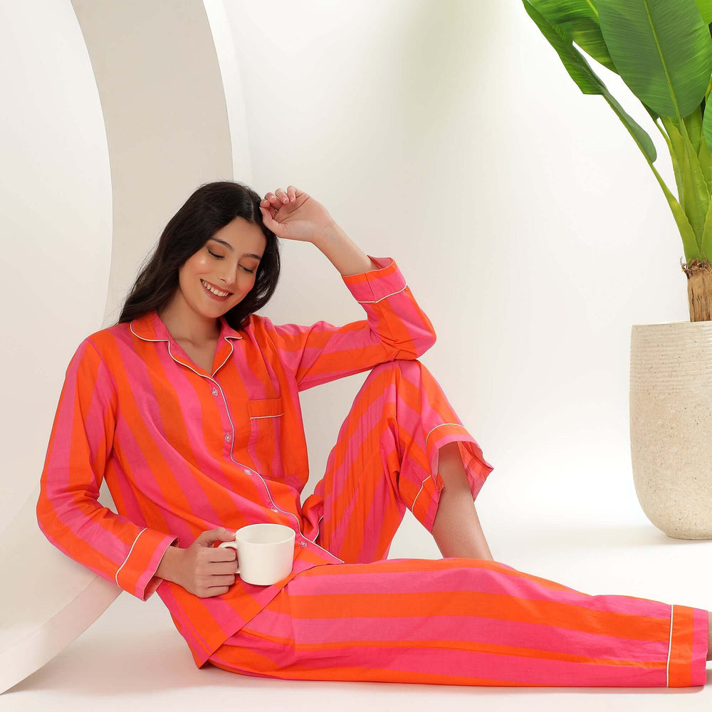 A woman in striped cotton pajamas for women, sitting with a cup in a modern setting, exuding comfort and style.