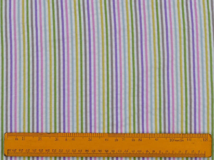 Woven stripe cotton fabric by the yard displayed with a ruler for scale, featuring vibrant pastel stripes.
