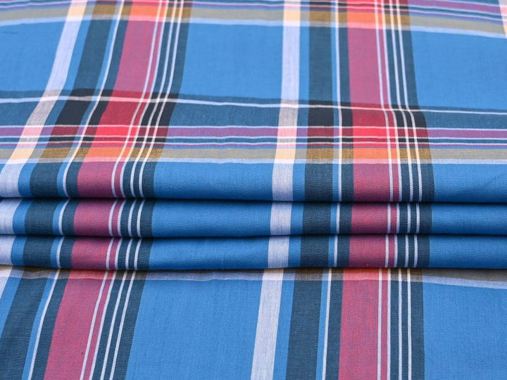 woven plaid tartan fabric by the yard in blue and red hues, ideal for sewing projects, displayed in folded layers.