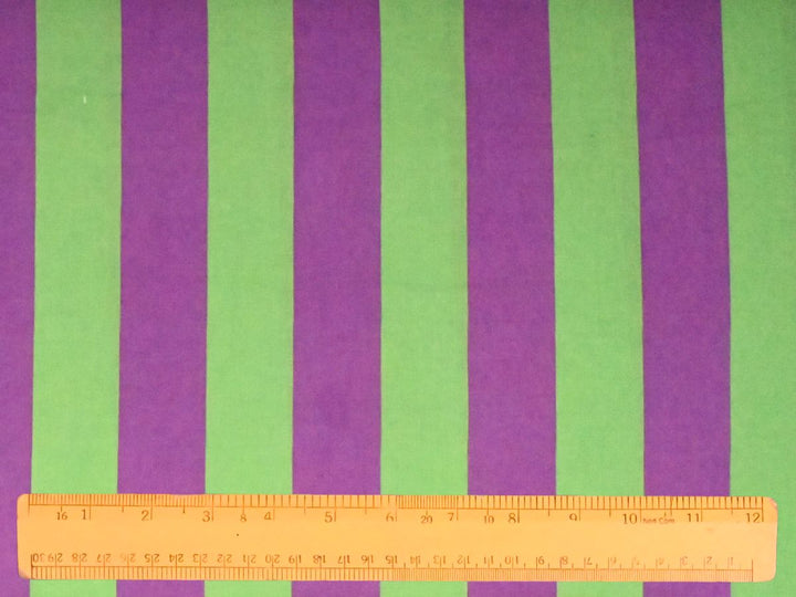 Softly layered folds of Indolibas purple and green printed stripe fabric showing its lightweight drape.