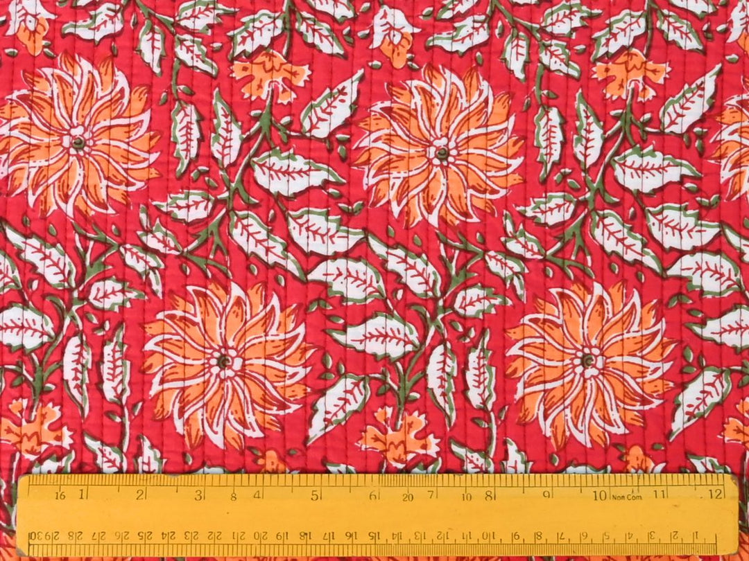Red quilted fabric showing floral print and red white striped reverse