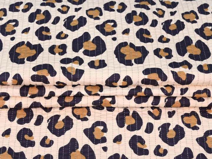 Close-up of leopard rosette quilted fabric with tan centers and navy spots
