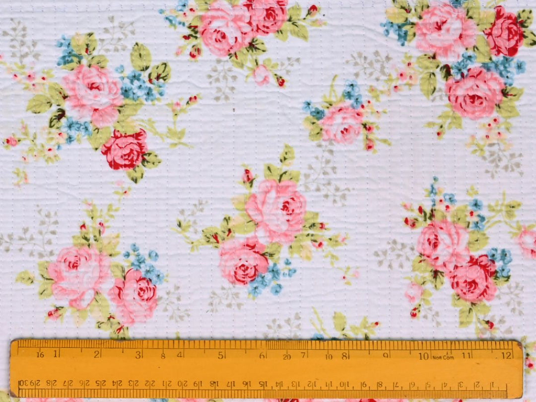 Folded pink floral quilted fabric showing texture and quilted stitching