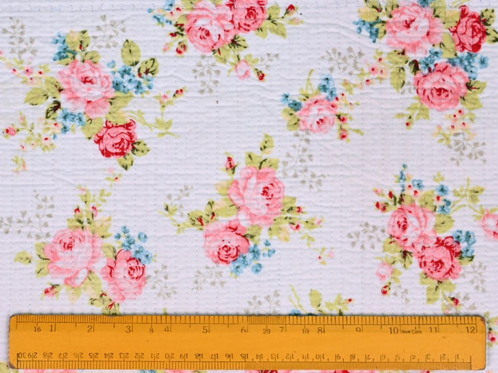 Folded pink floral quilted fabric showing texture and quilted stitching