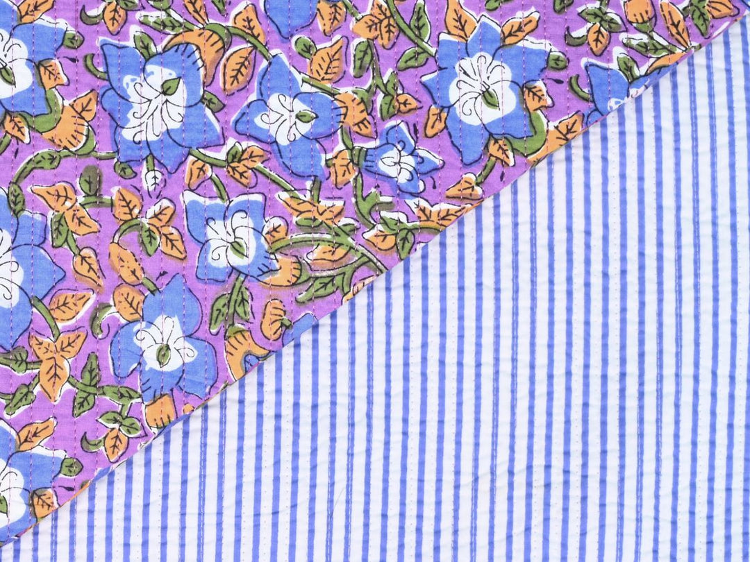 Purple floral quilted fabric with blue flowers and orange leaves