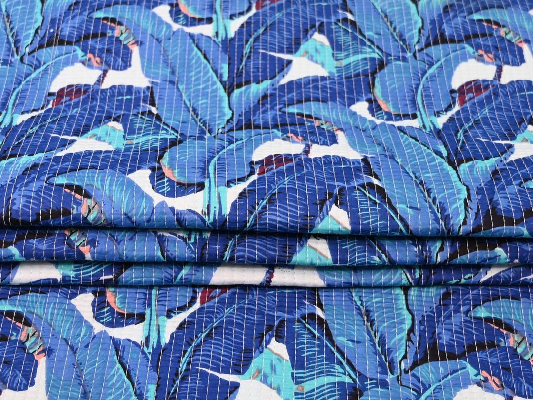 Close-up of tropical leaf quilted cotton fabric with teal and coral details