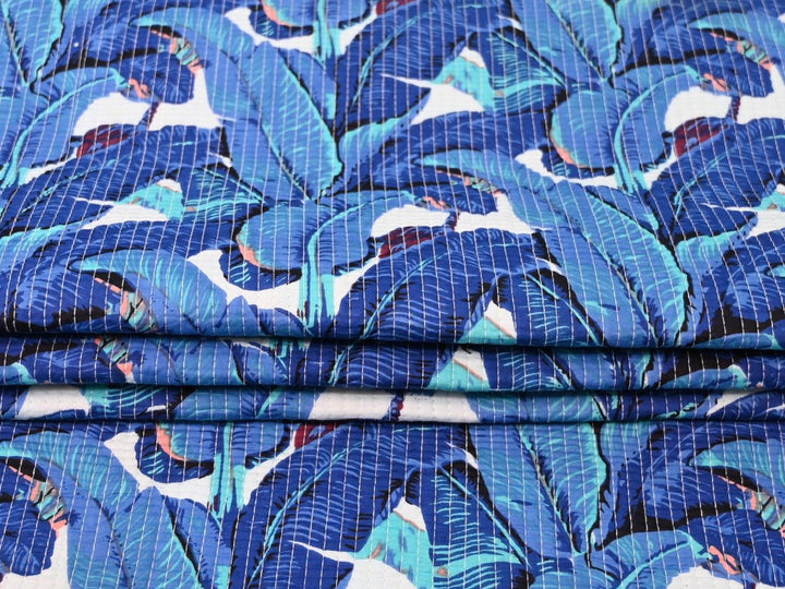 Close-up of tropical leaf quilted cotton fabric with teal and coral details