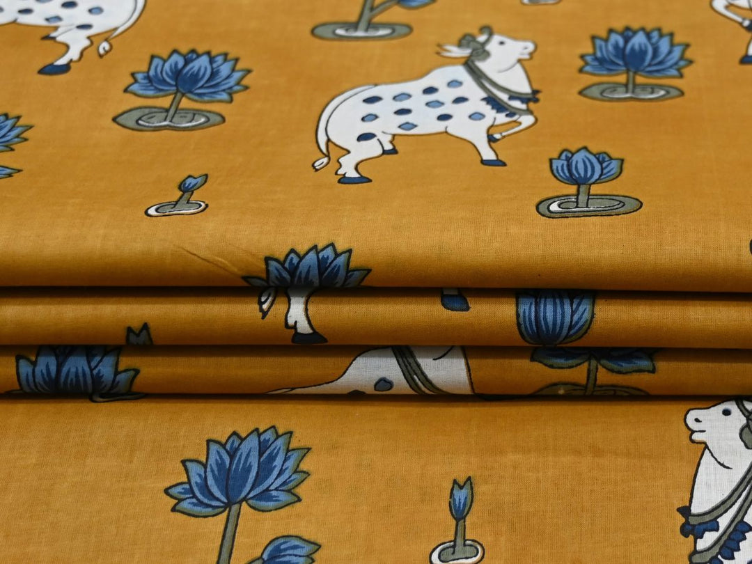 Printed cotton fabric with folk art cow and lotus design on mustard