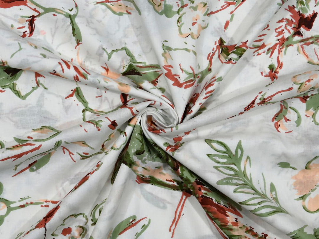 White cotton fabric showing loose floral sprays in reds and greens