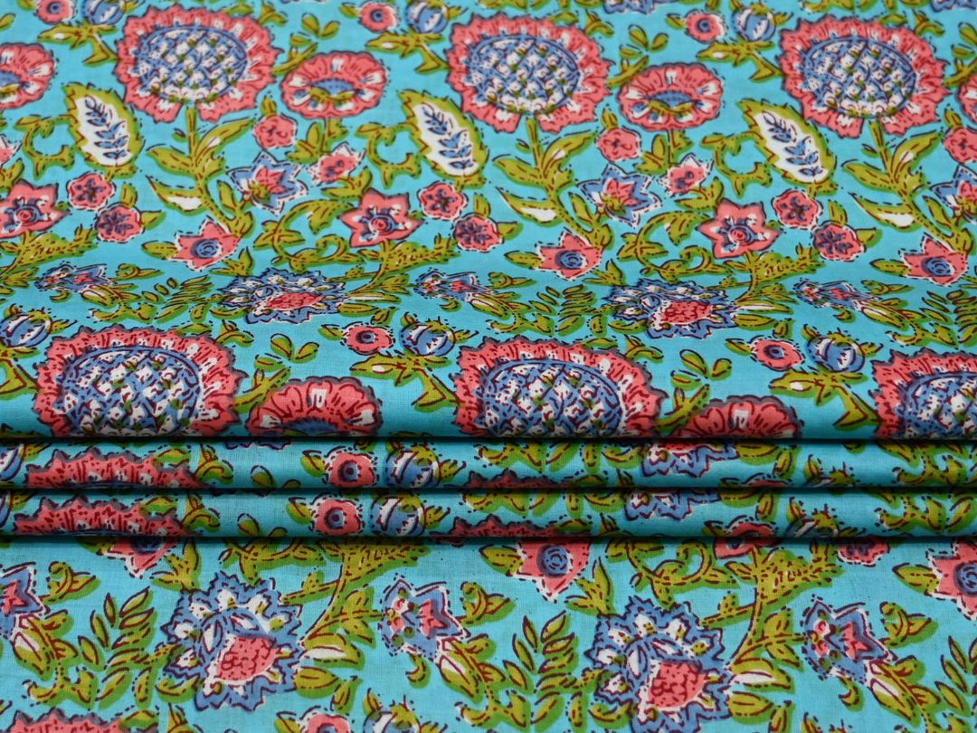 Close-up of sky blue block print fabric with pink, green, and teal floral details
