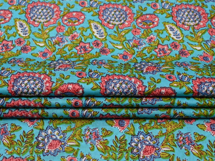 Close-up of sky blue block print fabric with pink, green, and teal floral details