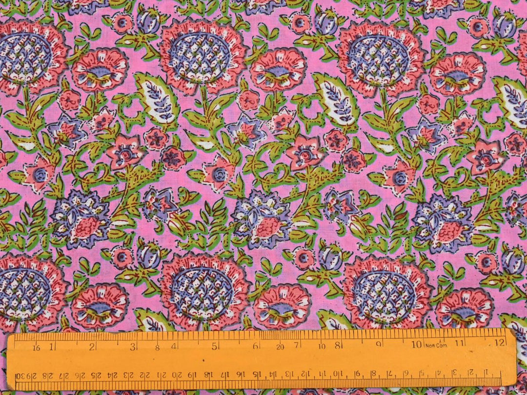 Dense floral block print fabric showing pink blooms and berry accents