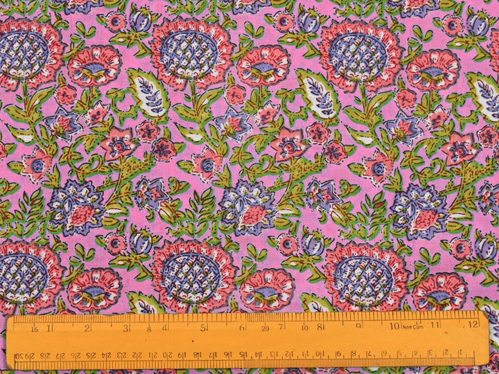 Dense floral block print fabric showing pink blooms and berry accents