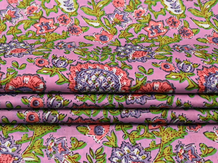 Close-up of green block print fabric with pink, blue, and purple floral details