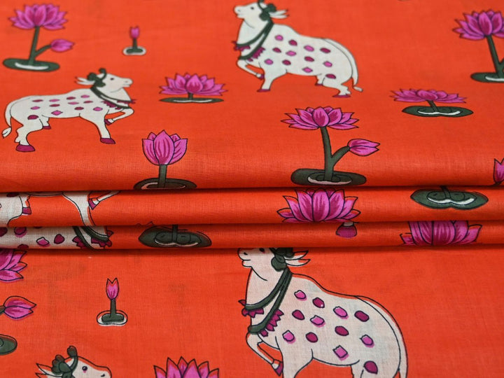 Close-up of Pichwai-style cotton fabric with cow and lotus details on orange