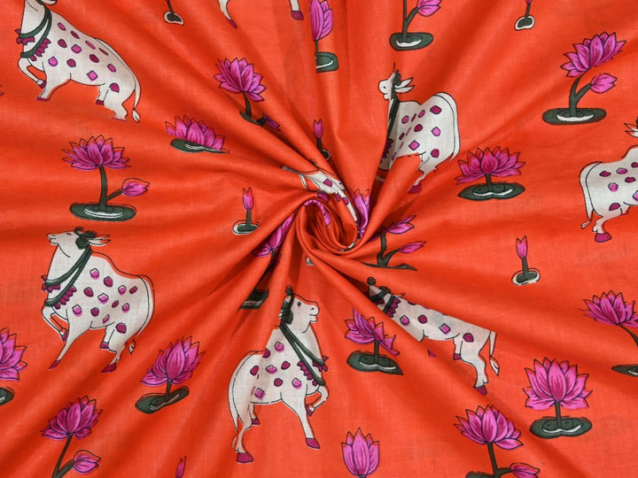 Orange Indian cotton fabric showing white cows with pink spots and lotus flowers
