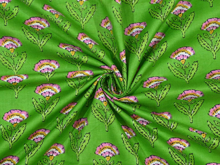 Green block print cotton fabric showing pink and yellow fan-shaped flowers