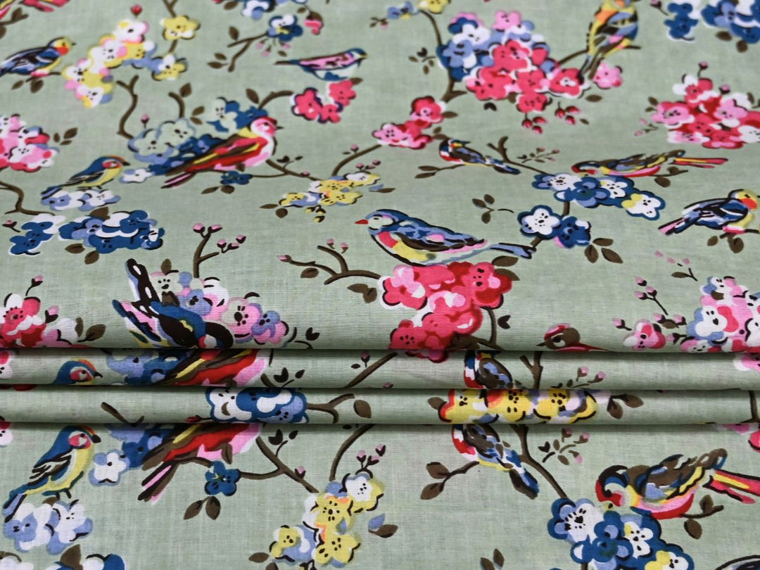 Close-up of bird and blossom print cotton fabric with pink and blue details