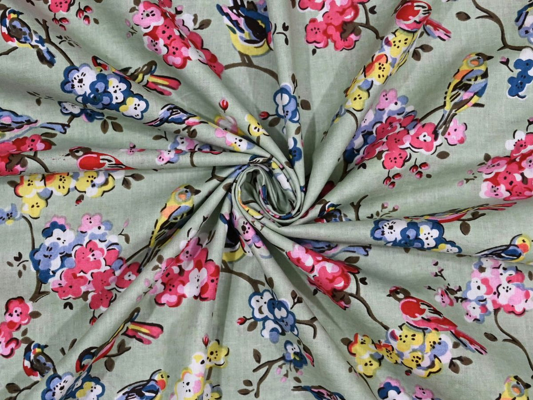 Sage green cotton fabric showing multi-colored birds on flowering branches