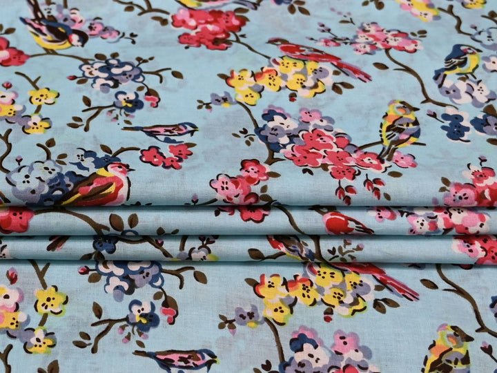 Close-up of grey bird and blossom print cotton fabric with pink and yellow details