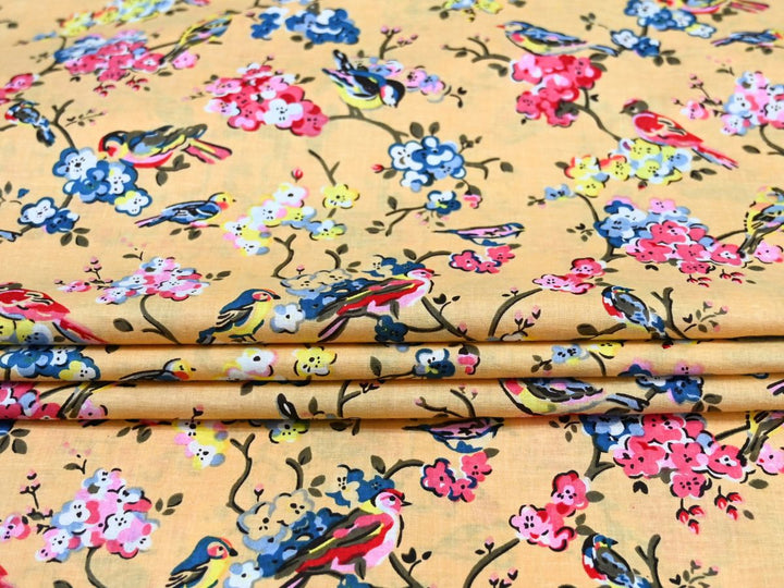 Close-up of yellow bird and blossom print cotton fabric with pink and blue details