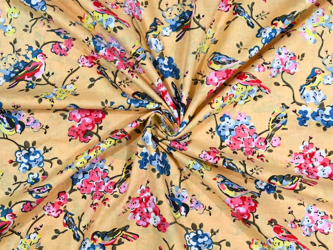 Yellow cotton fabric showing multi-colored birds on flowering branches