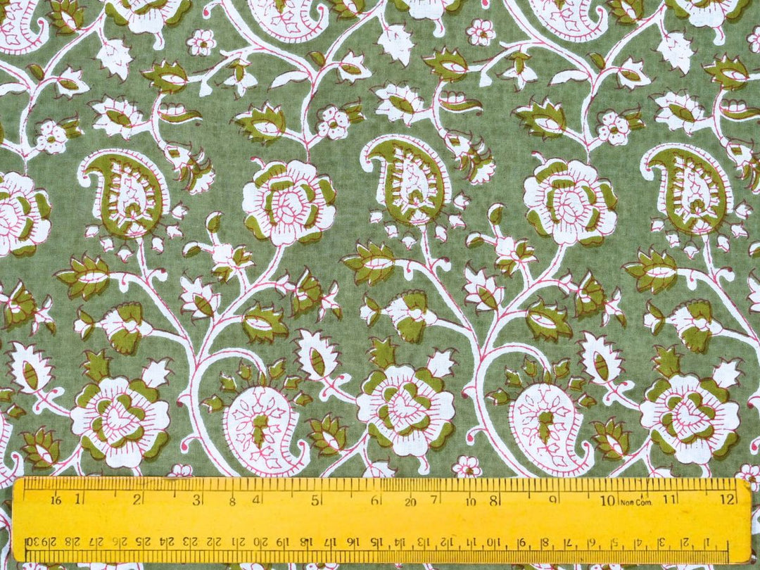 Close-up of green paisley cotton fabric with pink outlines and vine details