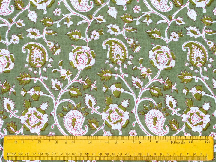 Close-up of green paisley cotton fabric with pink outlines and vine details