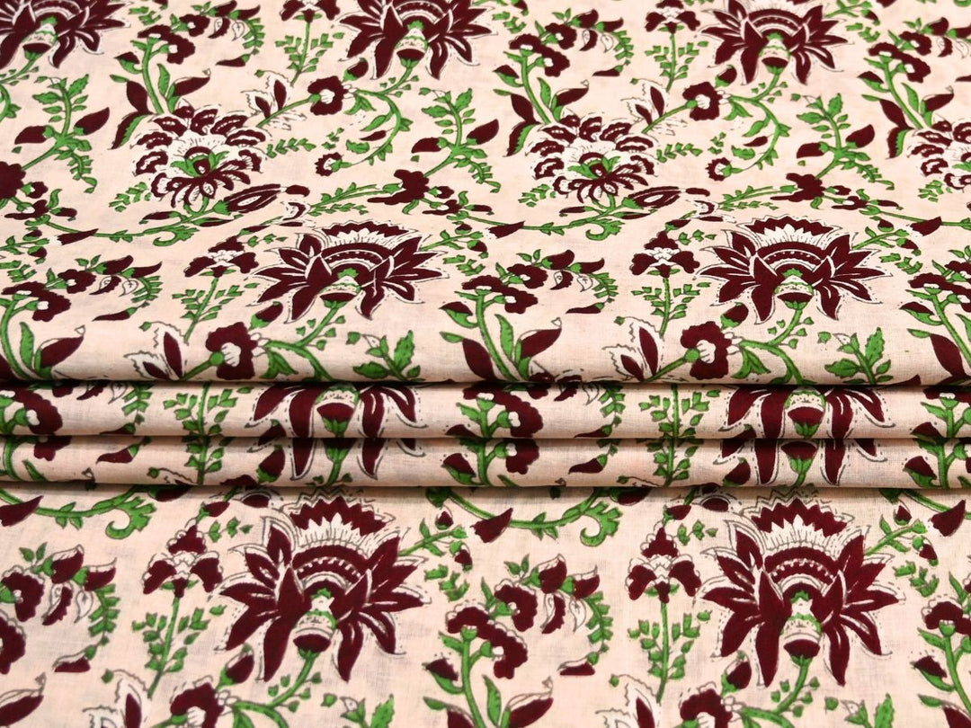 Close-up of cream block print fabric with maroon scalloped petals and white details
