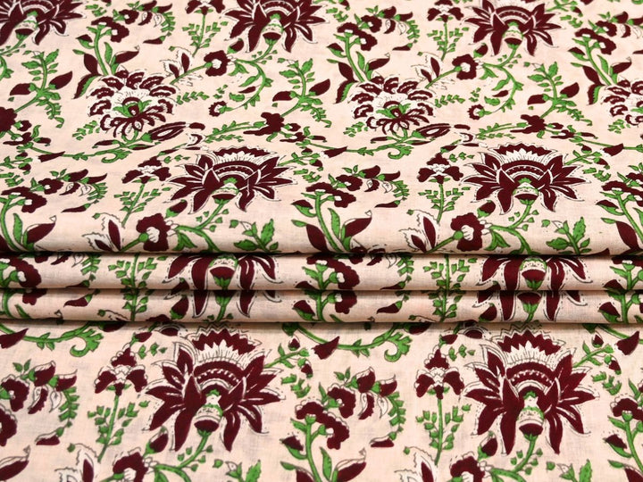 Close-up of cream block print fabric with maroon scalloped petals and white details