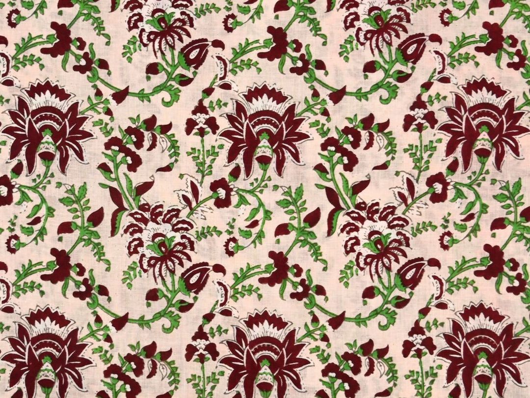 Cream cotton fabric showing maroon stylized flowers with green vines