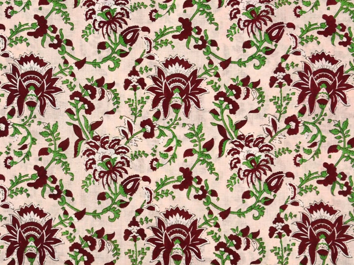 Cream cotton fabric showing maroon stylized flowers with green vines