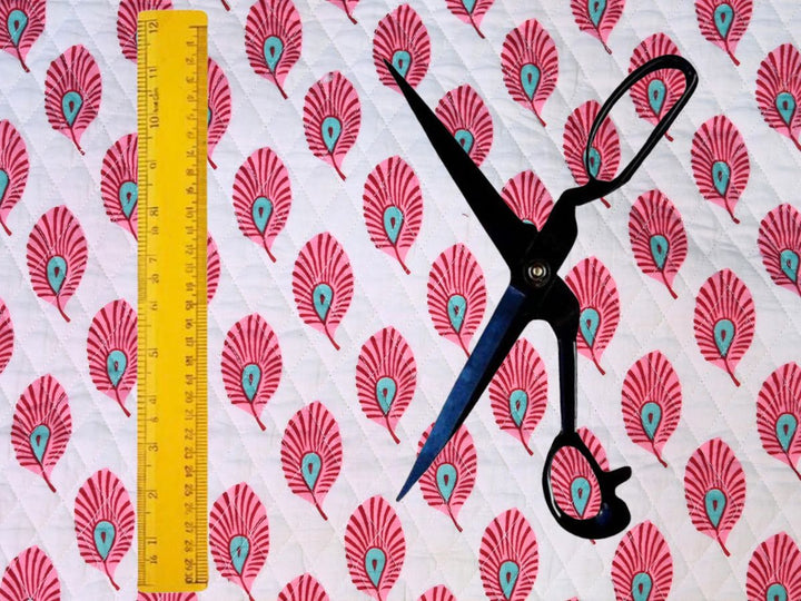White quilted cotton fabric showing pink fan-shaped feather motifs