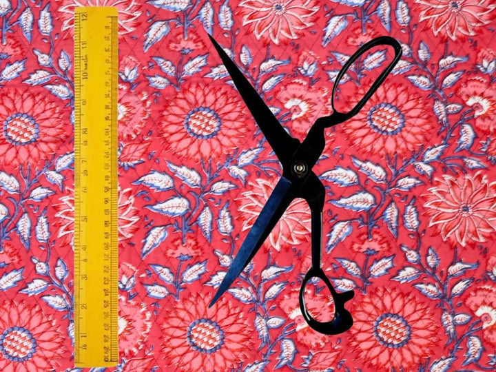 Red quilted cotton fabric showing dense floral motifs and blue leafy stems