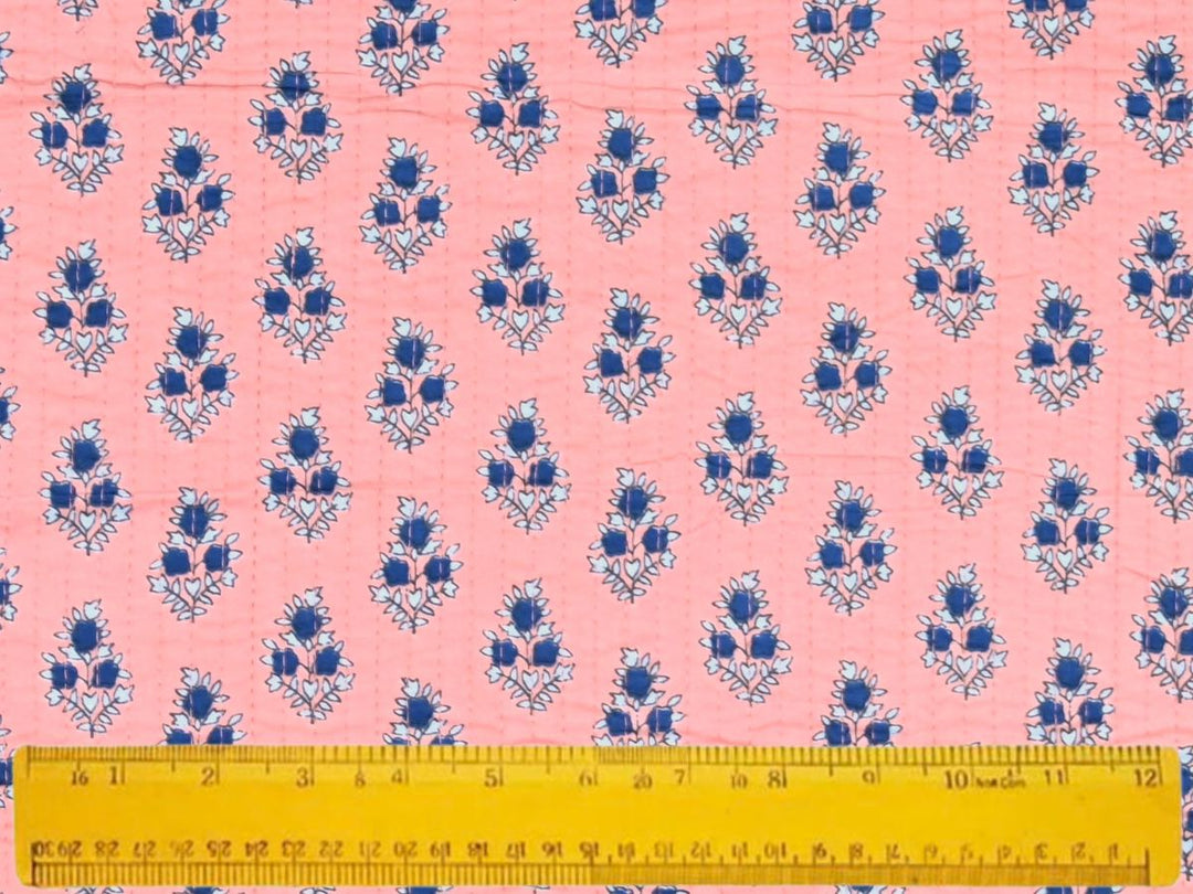 Close-up of peach quilted floral fabric with green stems and stitch lines