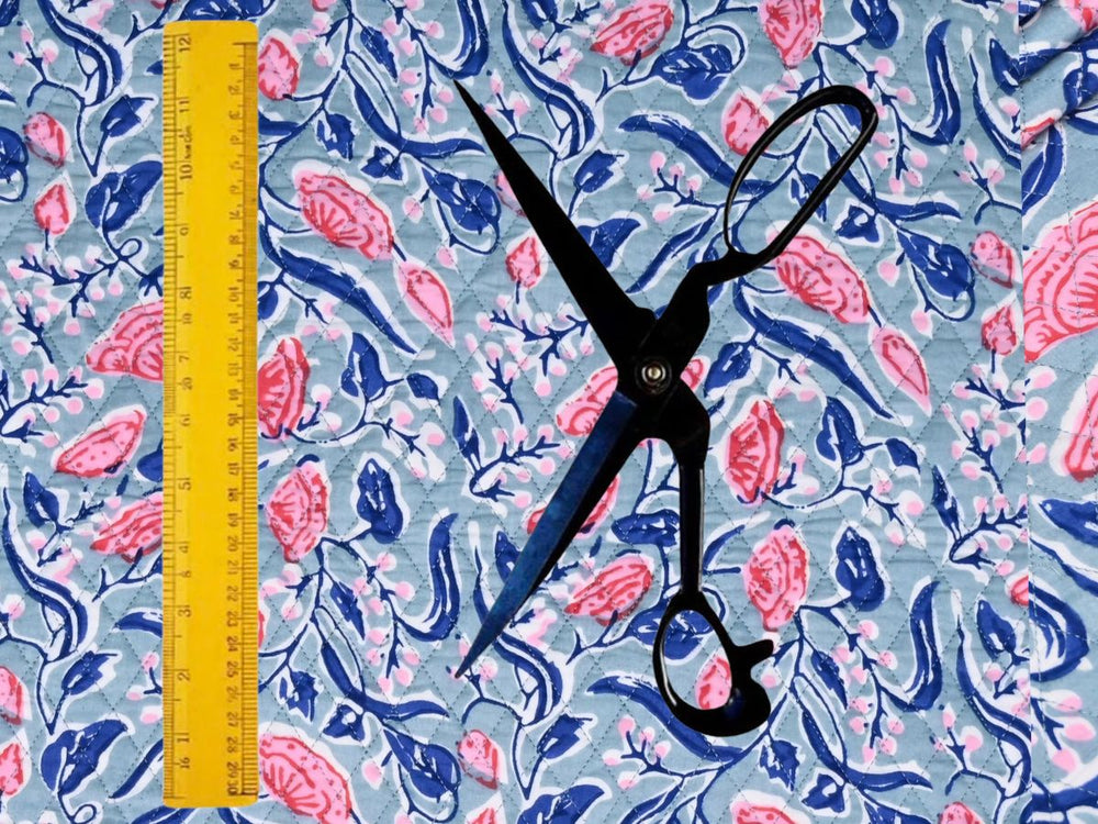 Dusty blue quilted cotton fabric showing coral blooms and navy foliage