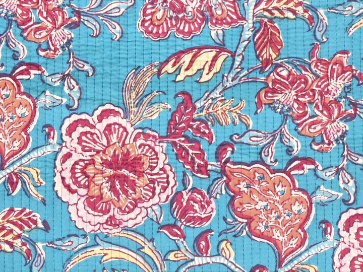 Close-up of teal quilted fabric with diamond stitch lines and dotted leaf details