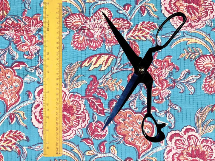 Turquoise quilted cotton fabric showing pink and coral peony blooms