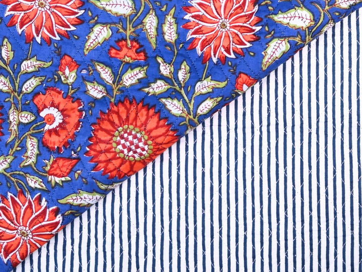 Cobalt blue quilted fabric by the yard with red-orange sunburst floral print